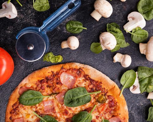 close-up-top-view-pizza-mushrooms-tomatoes-leaves-pizza-knife-dark-wooden-background_482257-34253